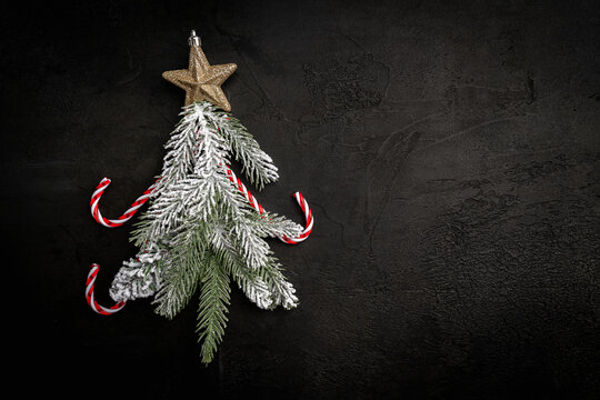 Christmas tree made of fir branches and Christmas and decorations accessories on black background. flat lay, top view. Christmas and New Year holiday card