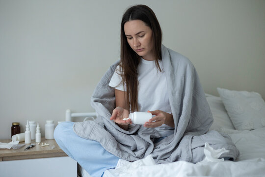 Sick woman resting in bed with symptoms of fever, runny nose and cough during an illness