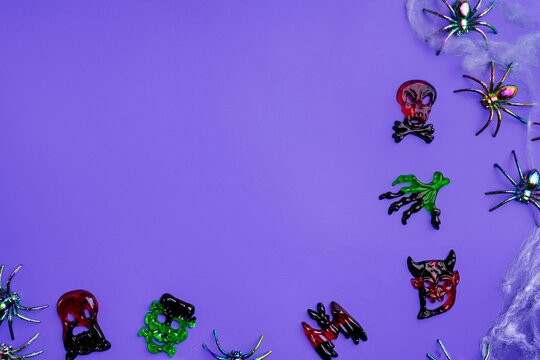 A modern greeting card for Halloween. Cobwebs, spiders, bats and candies, a ghost on a fashionable purple background. A banner with a place to copy the text. Top view. Flat Lay.