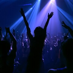 Silhouetted crowd in a nightclub with hands raised under blue and purple lights. © Susana