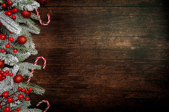 Christmas and New Year background with a festive scene with gold and red Christmas ornaments and fir tree branches on a wooden background, symbolizing holiday spirit and elegance.