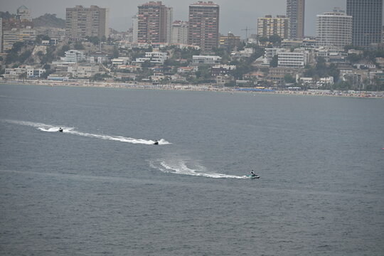 Three Jet Skis Speeding Across the Sea with Benidorm Beaches and Skyline in the Background