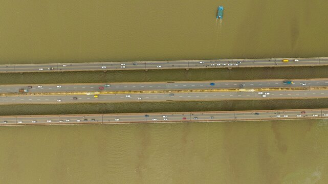 Aerial view of Atal Setu bridge spanning the Mandovi River with flowing traffic and a small boat navigating the water in Panaji, Goa, India.