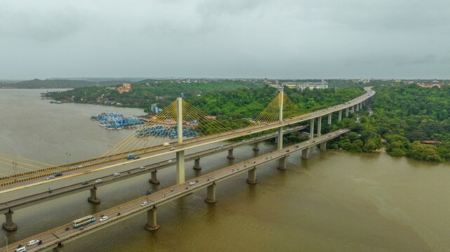 Aerial view of Atal Setu bridge spanning the Mandovi River with traffic flowing across the cable-stayed structure surrounded by lush greenery in Panaji, Goa, India.