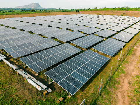 Aerial view of a large solar farm with rows of photovoltaic panels installed in a rural landscape in Ogun State, Nigeria.