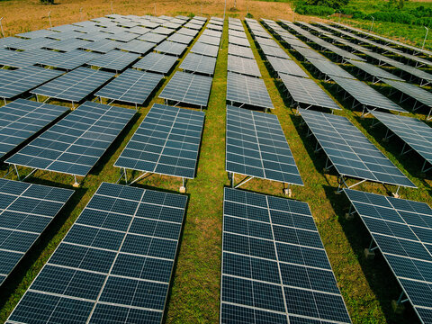 Aerial view of a large solar panel farm with rows of photovoltaic panels installed on a grassy field in Ogun State, Nigeria.