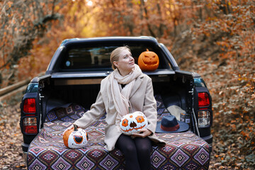Autumn road trip with a woman, colorful Halloween pumpkins and a pickup truck, combining outdoor leisure and festive creativity. © Olga