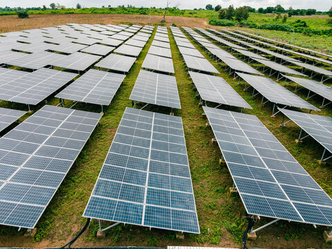 Aerial view of a large solar farm with rows of photovoltaic panels installed on green grassy fields in Ogun State, Nigeria.