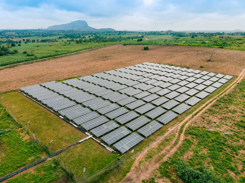 Aerial view of a large solar farm with rows of photovoltaic panels installed in a rural landscape in Ogun State, Nigeria.