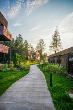 Pathway. Landscaped pedestrian path in modern residential area with greenery, low-rise buildings. Walking area in residential complex. Winding concrete path cuts through shrubs, and trees.