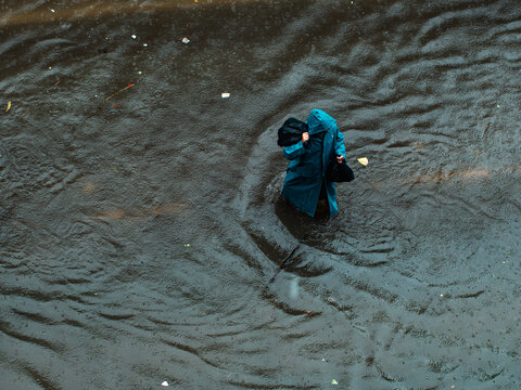Aerial View of Person in Raincoat Wading Through Flooded Street During Monsoon Rain