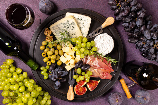 Charcuterie platter with cheese, wine, grapes, and prosciutto