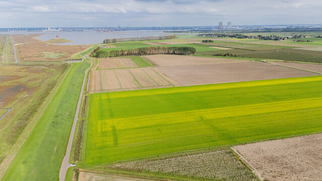 Aerial view showing doel nuclear power station towers and industrialized harbor area contrasting with agricultural fields and wetlands