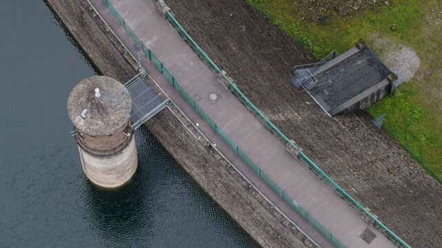 Aerial view of the Sengbachtalsperre dam featuring its stone intake tower, pedestrian walkway with green railings, and reservoir water in Solingen, Nordrhein-Westfalen, Germany.