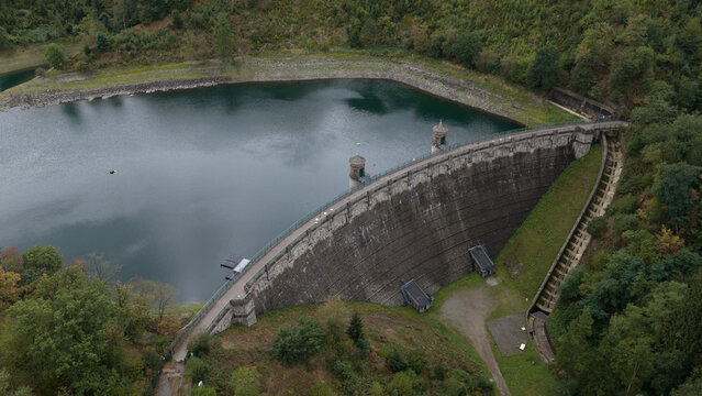 Aerial view of the Sengbachtalsperre dam with its stone masonry wall and reservoir surrounded by dense forest in Solingen, Nordrhein-Westfalen, Germany.