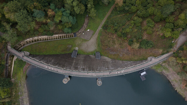 Aerial view of Sengbachtalsperre dam with its curved concrete wall and surrounding dense forest in Solingen, Nordrhein-Westfalen, Germany.