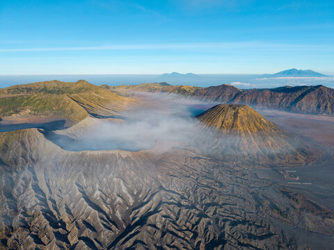 Aerial view of Mount Bromo sunrise over the volcanic caldera with mist swirling around the rugged terrain in Tosari, East Java, Indonesia.