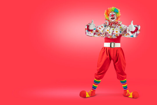Funny clown thumbs up, man entertainer as Joker in a suit and wig, with clown whiteface makeup. Trickster, jester, pantomime, mime, and a professional actor at events.
