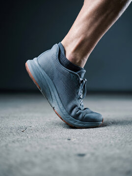 Close-up of an athlete foot in a grey running shoe pushing off a concrete surface during workout