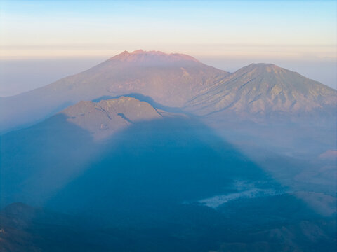 Aerial view of the Ijen volcano complex at sunrise with rugged peaks, volcanic slopes, and soft morning mist in Ijen, East Java, Indonesia.