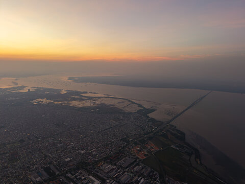 Aerial view of the Suramadu Bridge spanning the Madura Strait at sunset with urban sprawl in Surabaya, East Java, Indonesia.