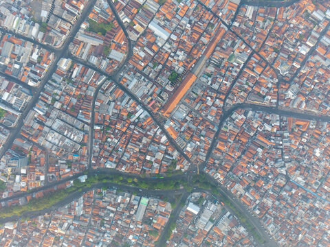 Aerial view of the historic Surabaya old town with dense terracotta-tiled rooftops, narrow streets, and a winding river in Surabaya, East Java, Indonesia.