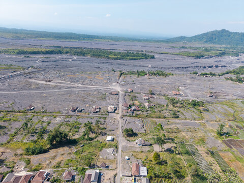 Aerial view of Supiturang Village showing the aftermath of the Mount Semeru volcanic eruption with volcanic ash covering the landscape and scattered houses in Pronojiwo, East Java, Indonesia.