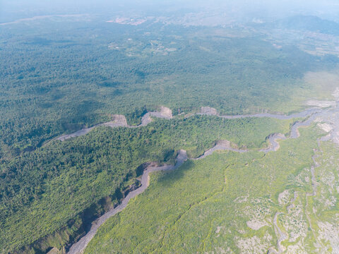 Aerial view of the volcanic debris path cutting through the lush green forest near Mount Semeru in the Supiturang area of Pronojiwo, East Java, Indonesia.