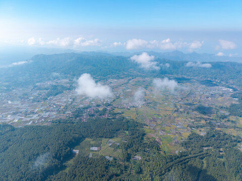 Aerial view of the rural landscape of Sumberurip, featuring agricultural fields, lush forests, and scattered village houses in Pronojiwo, East Java, Indonesia.