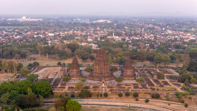 Aerial view of the historic Prambanan Temple complex with towering stone spires, intricate carvings, and lush greenery in Kecamatan Prambanan, Daerah Istimewa Yogya, Indonesia.