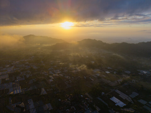 Aerial view of the sunrise over the Sumberurip area with mist-covered fields and rooftops in Pronojiwo, East Java, Indonesia.