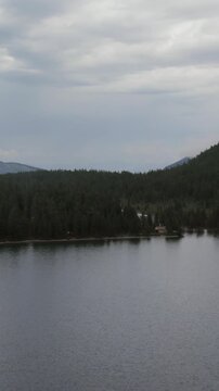 Drone footage of calm Multinsky Lakes surrounded by dense taiga forest and mountain ridges under dramatic overcast clouds, Ust-Koksinsky District, Altai Republic, Russia