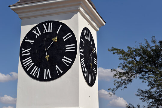 Historic clock tower with black clock faces and Roman numerals against a blue sky