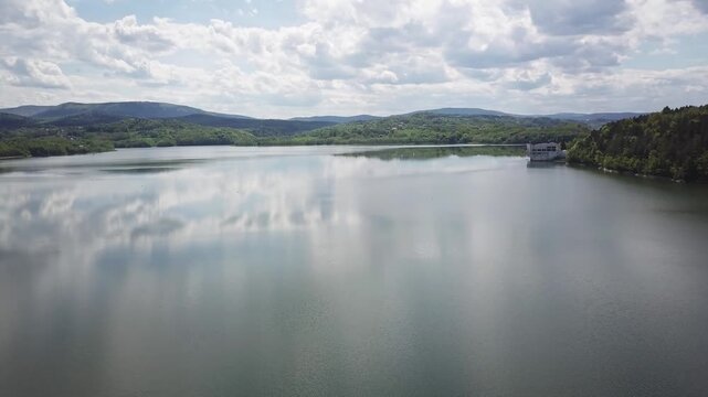 Shore of water reservoir with forest under blue sky at sunny summer day. Aerial view.