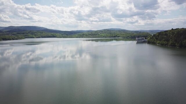 Shore of water reservoir with forest under blue sky at sunny summer day. Aerial view.