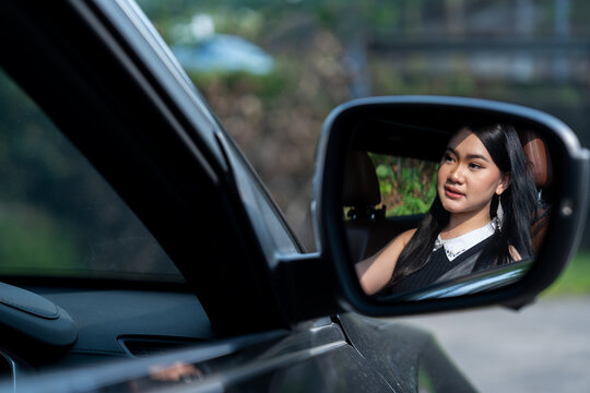 Reflection of Malay woman in side-view mirror of car