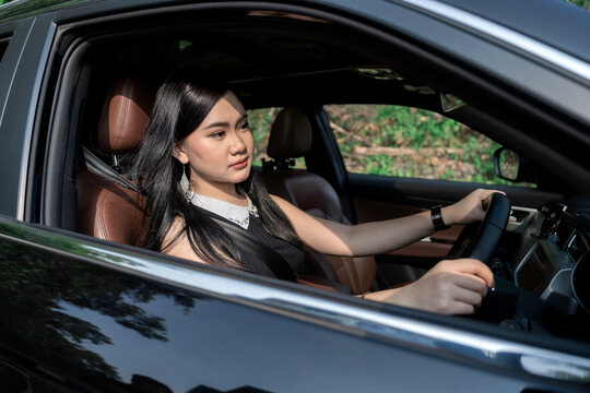 Serious young Asian woman driving a car