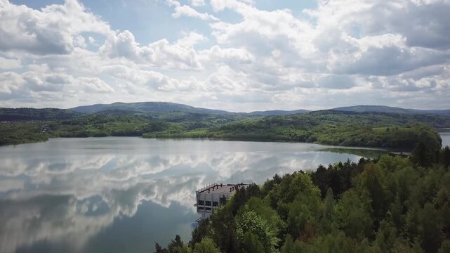 Shore of water reservoir with forest under blue sky at sunny summer day. Aerial view.