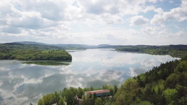 Shore of water reservoir with forest under blue sky at sunny summer day. Aerial view.