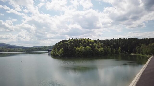 Shore of water reservoir with forest under blue sky at sunny summer day. Aerial view.
