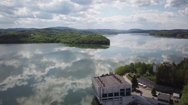 Shore of water reservoir with forest under blue sky at sunny summer day. Aerial view.