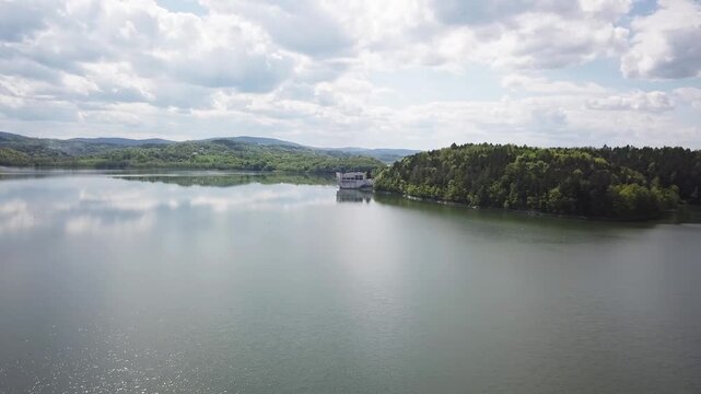 Shore of water reservoir with forest under blue sky at sunny summer day. Aerial view.