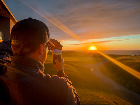 Inverness, Canada - September 18, 2026: Visitor photographs the sunset over the coastal fairways of Cabot Links golf course on Cape Breton Island.