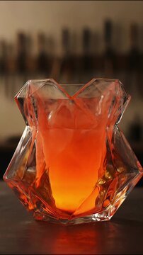 Geometric faceted glass vase glowing with vibrant orange liquid in motion stock video clip