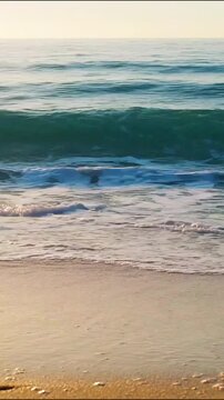 Ocean waves crashing gently onto sandy beach shore under bright morning sunlight video clip