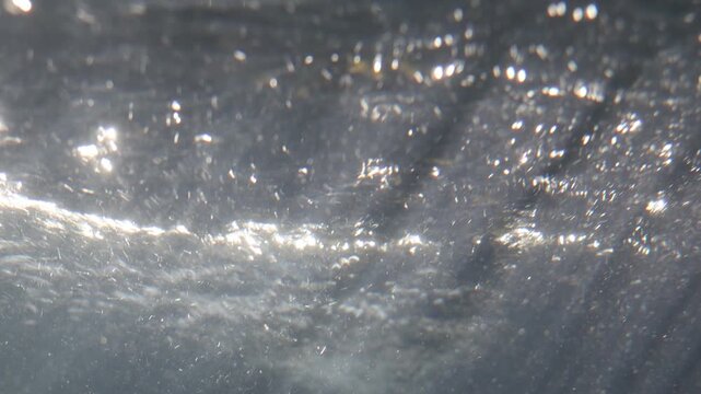 Abstract macro view of shimmering light reflections on a dark textured liquid surface