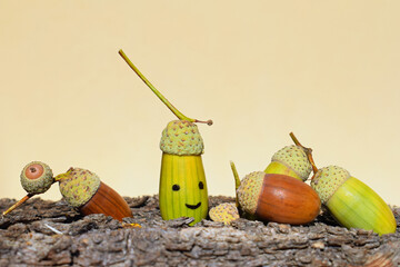 Green and brown acorns, with one painted smiling acorn, copy space for text. Autumn season © Martina