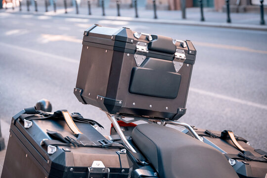 Motorcycle equipped with aluminum top case and panniers, parked on a street, representing travel, road trips, and exploration