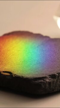 Rainbow light spectrum moving across dark textured stone surface video footage background clip