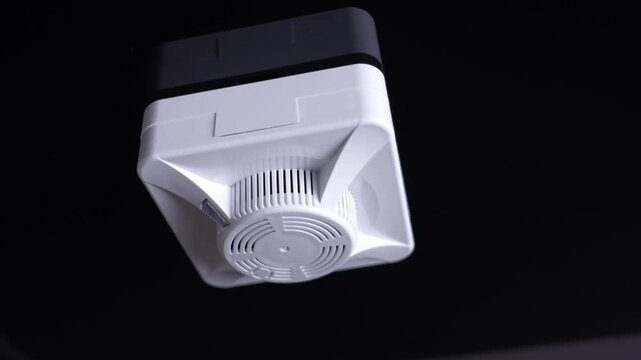 White plastic ceiling fan. Visible vent and housing details. Dark background emphasizes product. Modern design suitable for home interiors. Common household ventilation solution